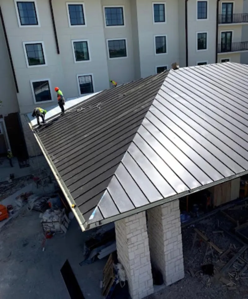 Crew installing standing seam metal roof panels on a commercial project in Melrose